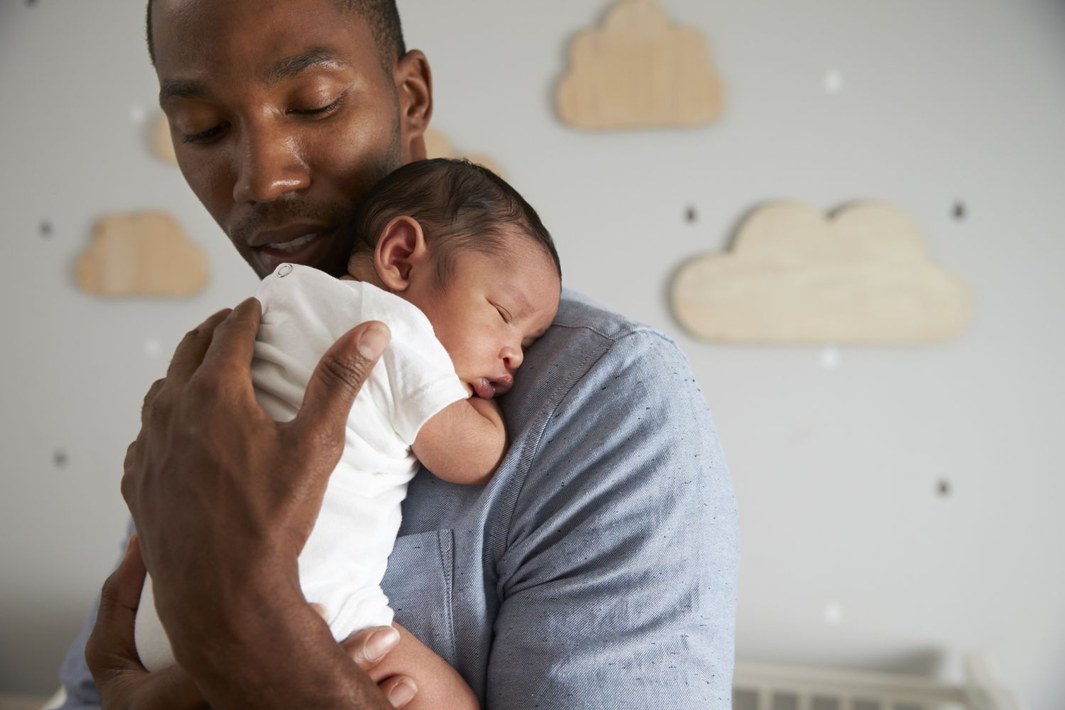 Ein Vater hält sein Neugeborenes auf dem Arm. Es leidet an einer Kolik. 