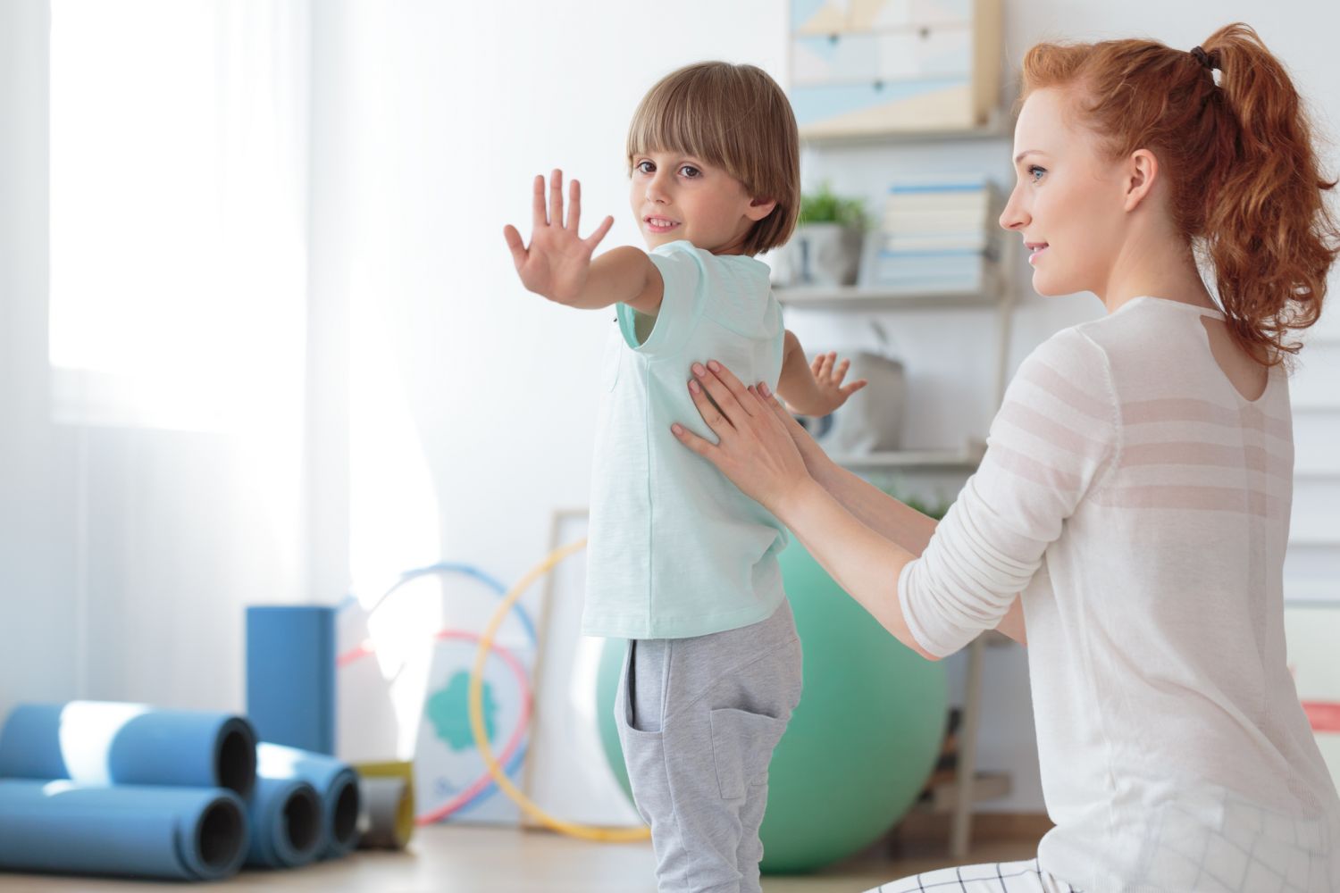 Therapeutin untersucht die Wirbelsäulenstellung bei einem kleinen Jungen.